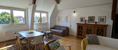 A spacious living area with a dining table, chairs, a sofa, and a cabinet.