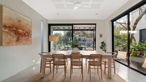 A dining area with a large table, six wicker chairs, a ceiling fan, and a view of the outdoors. - Villa Sorrento | The Perfect Escape (Sorrento)