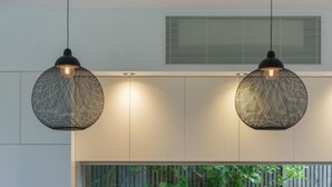 A modern kitchen with a wooden countertop, three bar stools, and two hanging pendant lights. - Villa Sorrento | The Perfect Escape (Sorrento)