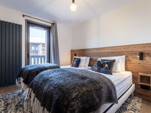 Quarto com cama, cabeceira de madeira, mesa de cabeceira e janela com cortinas.