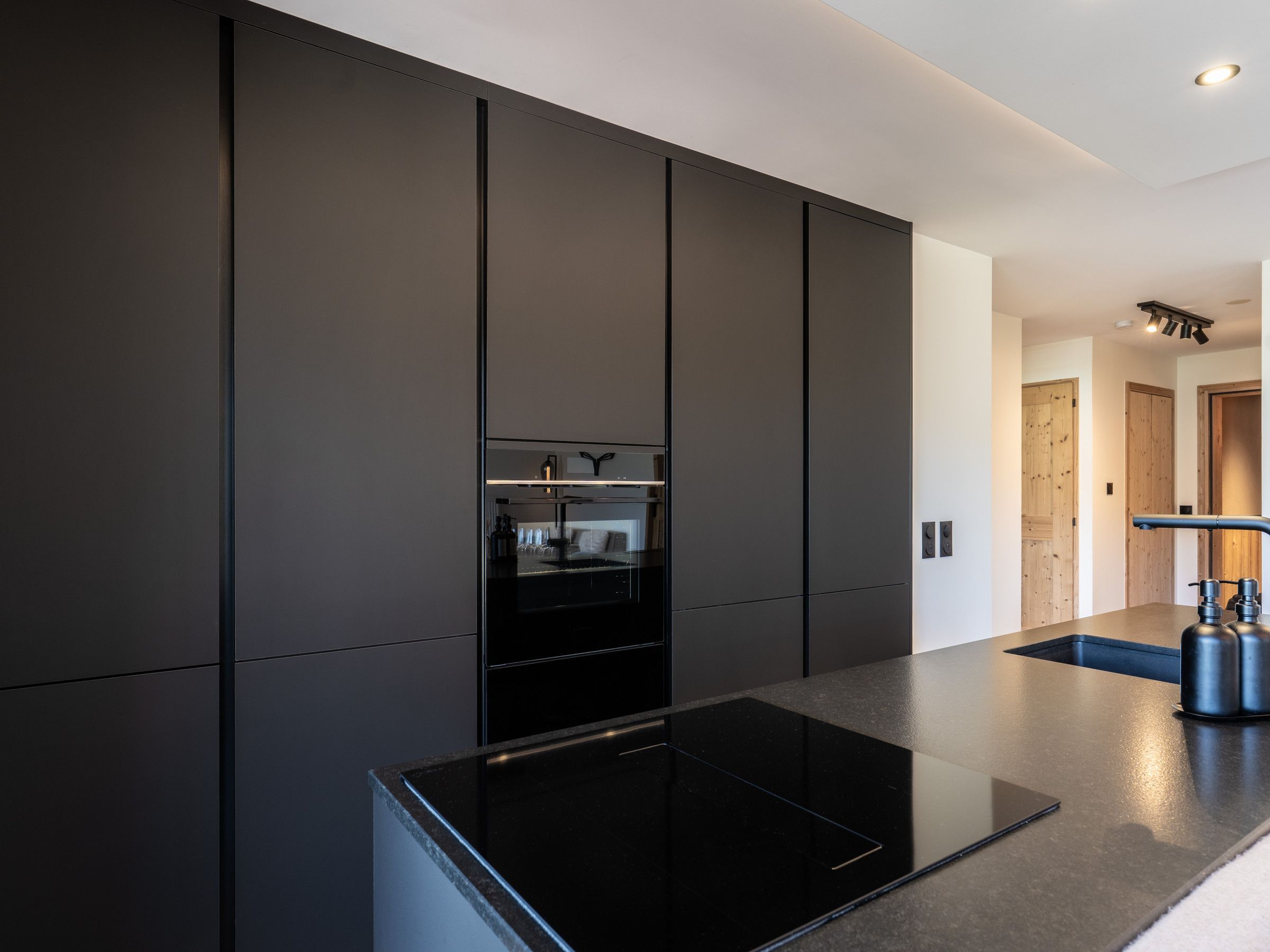 A modern kitchen with a black countertop, built-in appliances, and a minimalist design.