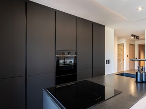 Uma cozinha moderna com bancada preta, eletrodomésticos embutidos e design minimalista.