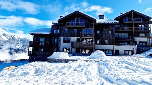 A multi-story wooden lodge with balconies and a mountain backdrop.