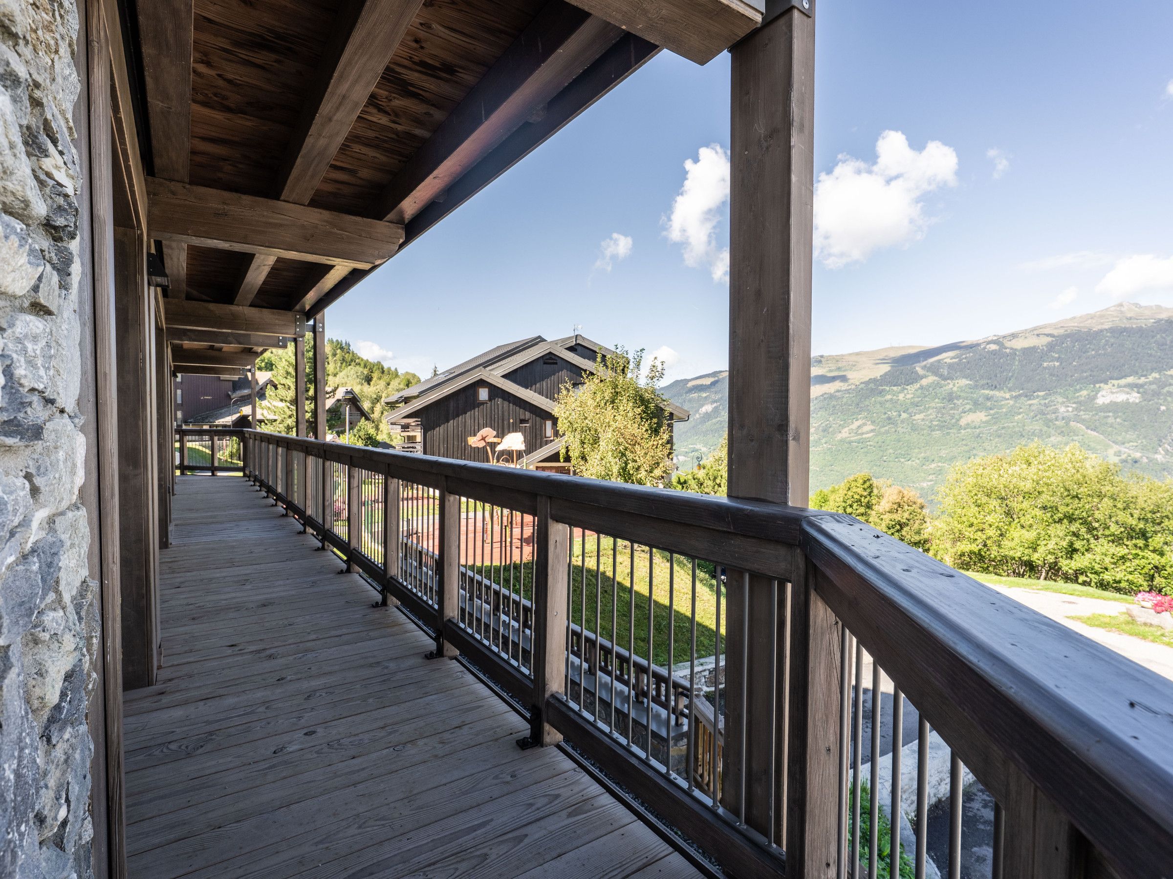 A wooden balcony with a railing overlooking a mountainous landscape.