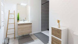 Ein modernes Badezimmer mit einem Holzkosmetikschrank, einem Spiegel, einem Waschbecken und einer Duschkabine.