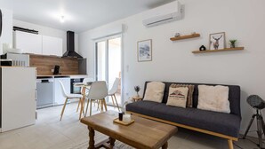 Ein modernes Wohnzimmer mit einer dunkelgrauen Couch, einem Holztisch und einem Essbereich mit weißen Stühlen.