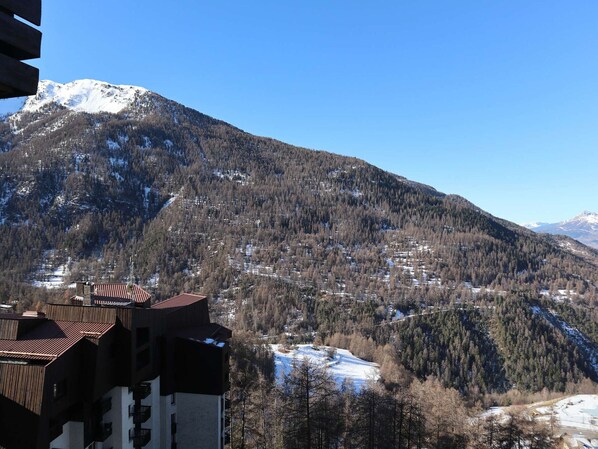 A mountain landscape with a building featuring a sloped roof and multiple balconies.