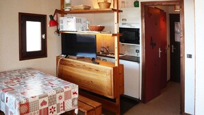 A compact kitchen with a wooden table, a built-in oven, and a refrigerator. - Studio at Les Orres 1650 for 4 pers, direct slopes access (Les Orres)