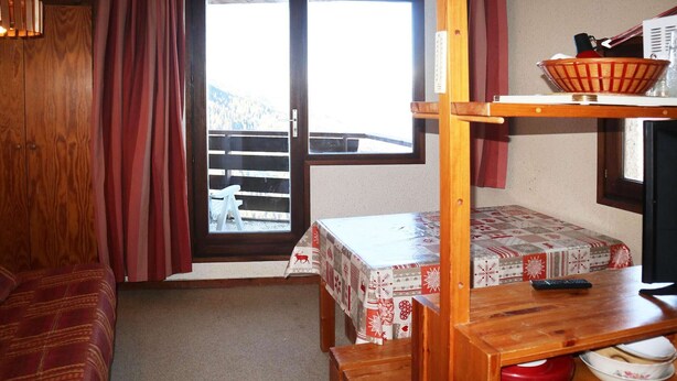 A cozy room with a wooden bunk bed, a small table with a basket, and a view of a balcony. - Studio at Les Orres 1650 for 4 pers, direct slopes access (Les Orres)