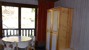 Ett rum med ett runt bord, stolar, ett träskåp och ett fönster med gardiner.