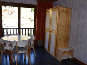 A room with a round table, chairs, a wooden cabinet, and a window with curtains. - Studio for 4 with Wifi, balcony in Valloire (Valloire)