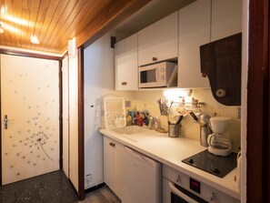 Een keuken met witte kastjes, een magnetron, een koffieapparaat en een vaatwasser.