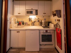 A compact kitchen with a microwave, coffee maker, toaster, and a dishwasher.