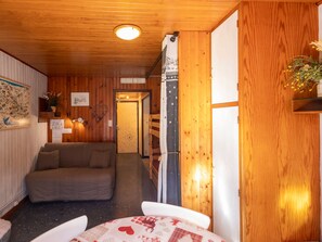 A cozy room with a wooden ceiling, a sofa, a table with a patterned tablecloth, and a door with a star-patterned curtain.