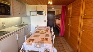 Una cocina compacta con una mesa de comedor, armarios de madera, un microondas y un lavabo.