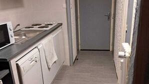 Cozinha estreita com fogão, pia e lava-louças.