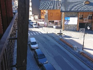 A street view with cars parked along the side, a building with a blue roof, and a signboard. - Studio West for 4 pers. in Valloire with balcony (Valloire)