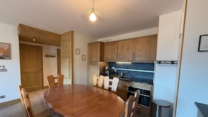 A modern kitchen with wooden cabinets, a stainless steel sink, and a round dining table with chairs. - New 3-room apartment, 6 guests, terrace, parking, Les Saisies (Villard-sur-Doron)