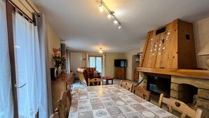 Un rincón comedor acogedor con mantel estampado, sillas de madera y chimenea de piedra.