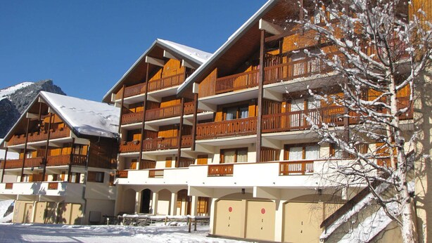 Ein mehrstöckiges Hotel mit Balkonen und verschneiter Landschaft.