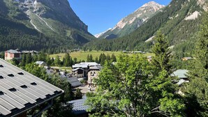 Ein Bergdorf mit traditioneller Bebauung, einem Tal und einem markanten Berggipfel.
