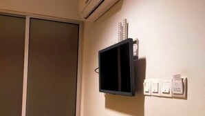 Una habitación con puerta corredera, aire acondicionado instalado en la pared, un televisor negro y varios enchufes eléctricos.