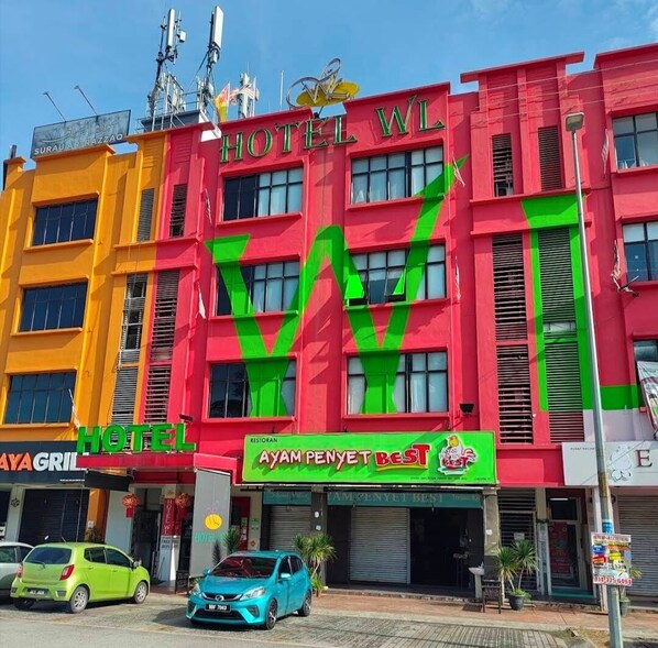 Um edifício de vários andares com fachada marcante em vermelho e amarelo, exibindo um grande logotipo 'W' e o nome 'Hotel W'.
