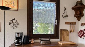 A wooden dresser with a coffee maker, a scale, and a wooden cutting board.