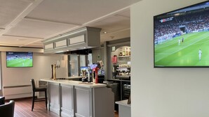A bar area with a counter, seating, and a television displaying a soccer match. - The Galleon Hotel, Hull City, Part of the AG Collection (Hull)