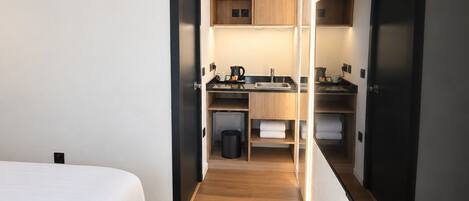 Una habitación de hotel moderna con cama, kitchenette y baño.