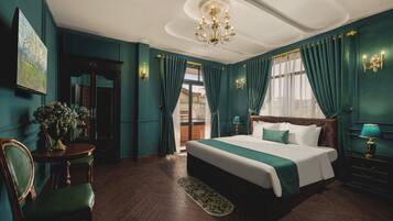 Een ruime slaapkamer met een groot bed, een kroonluchter en groene gordijnen.