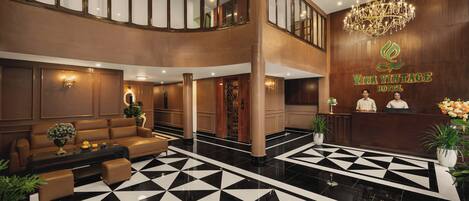 A lobby with a checkered floor, a reception desk, and a chandelier.
