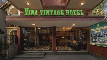 Das äußere Erscheinungsbild des Vina Vintage Hotels mit klassischem Design, inklusive einer Straßenschild-Reklame und einem aufwendig gestalteten Eingangsbereich mit einem gemusterten Boden.