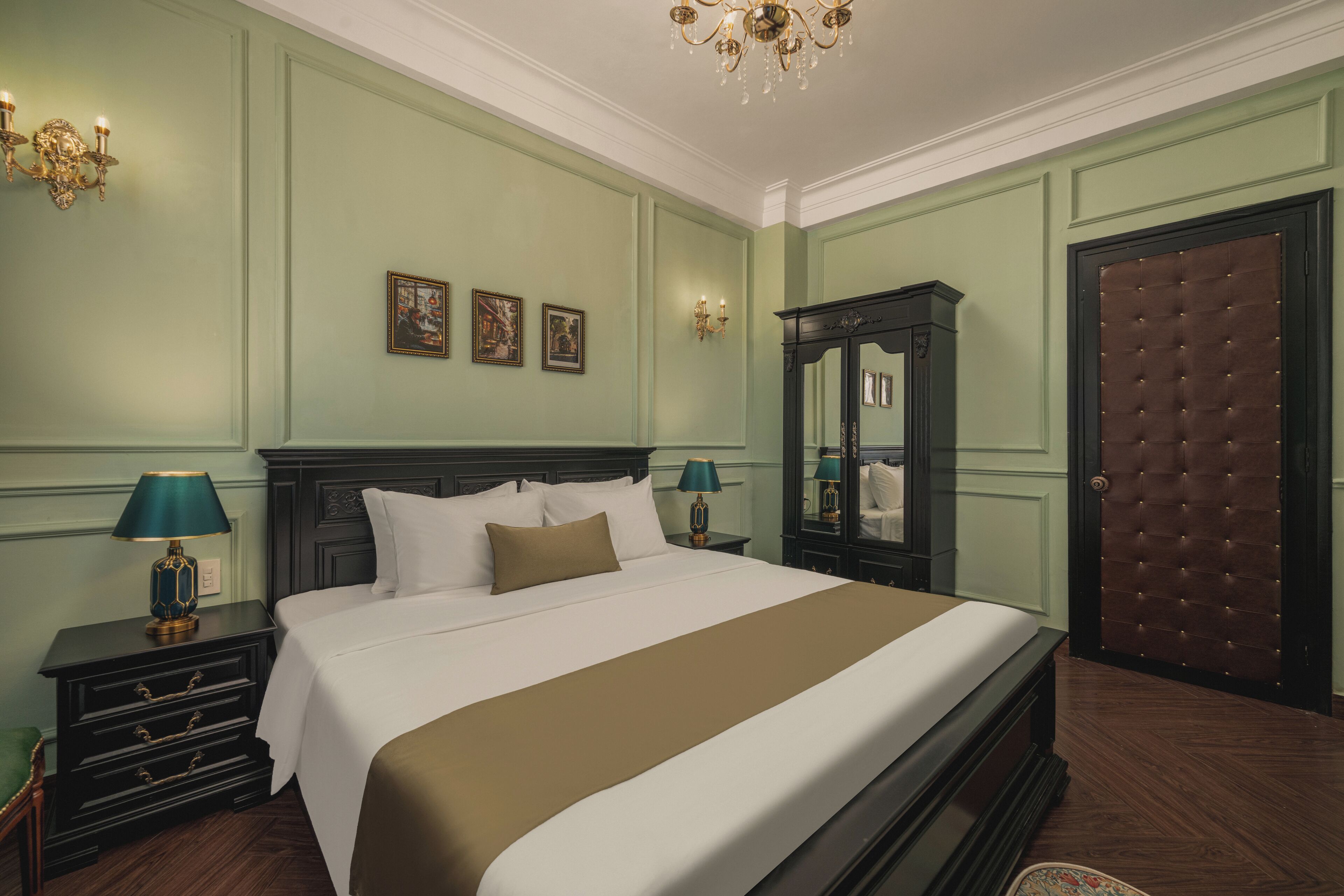 A neatly arranged bedroom with a large bed, a dresser, a mirror, and a door with a tufted panel.