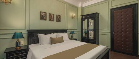 A neatly arranged bedroom with a large bed, a dresser, a mirror, and a door with a tufted panel.