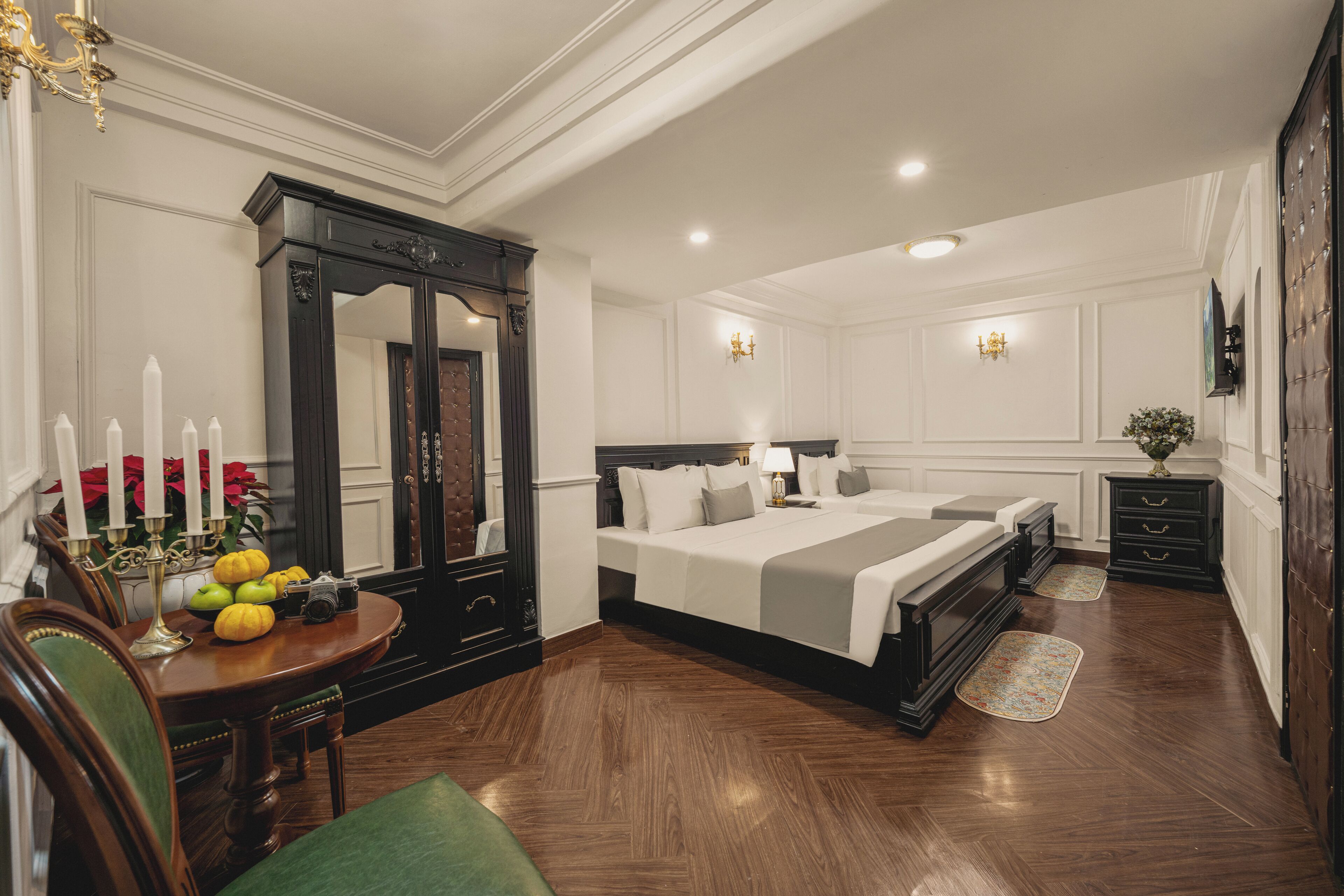 Une chambre spacieuse avec un grand lit, une commode, une coiffeuse et un coin repas avec une table mise pour deux personnes.