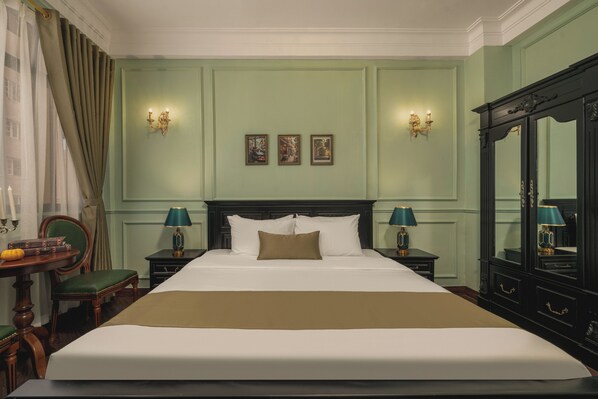 A well-appointed hotel room with a large bed, two bedside tables with lamps, a dresser, and a mirror.