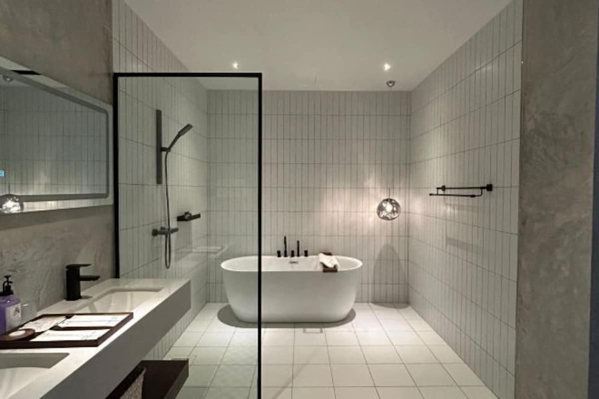 Un baño moderno con una bañera independiente, una ducha con mampara de vidrio y un tocador con espejo.