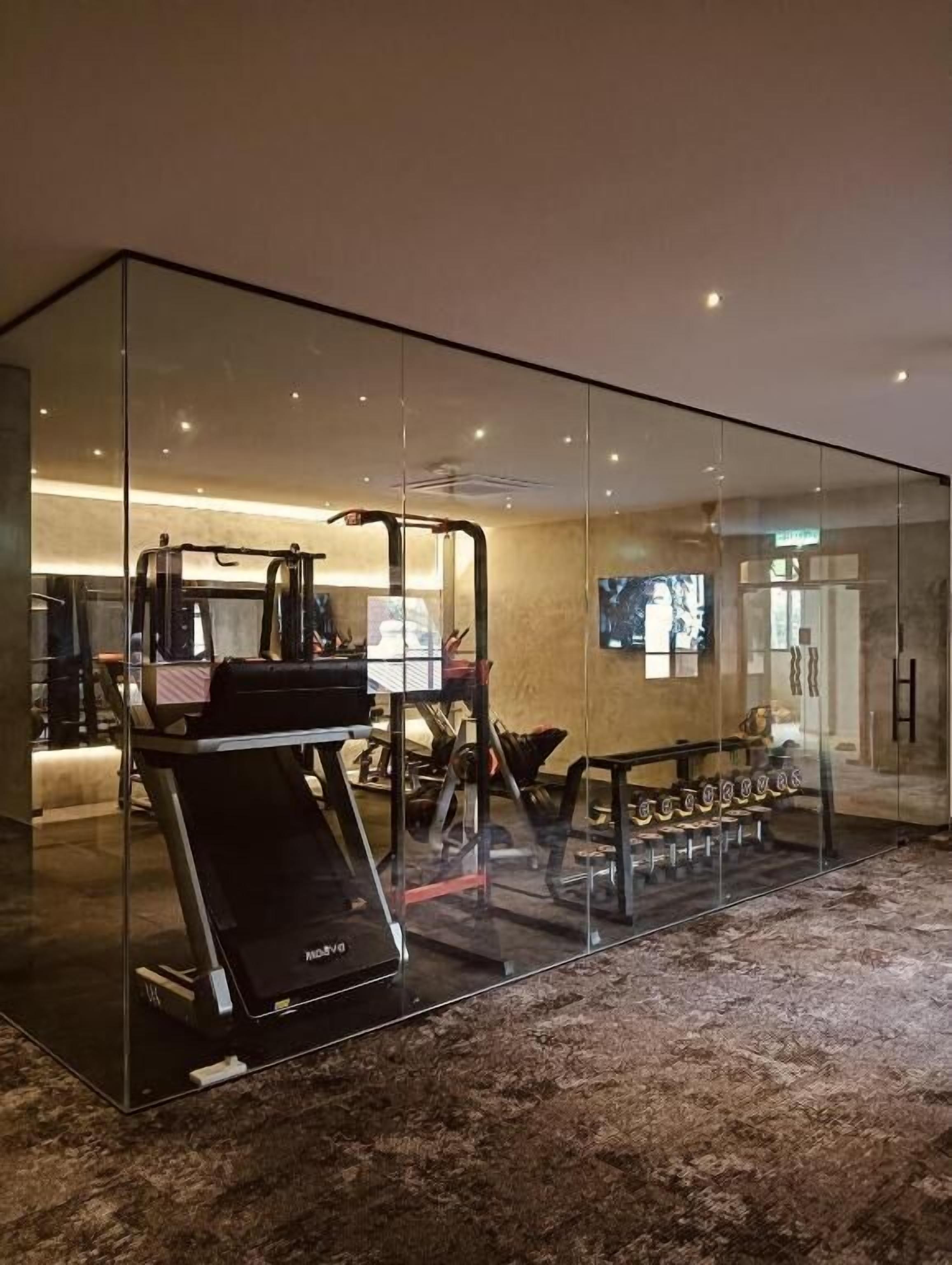 A modern gym with a mirrored wall, exercise equipment, and a television.