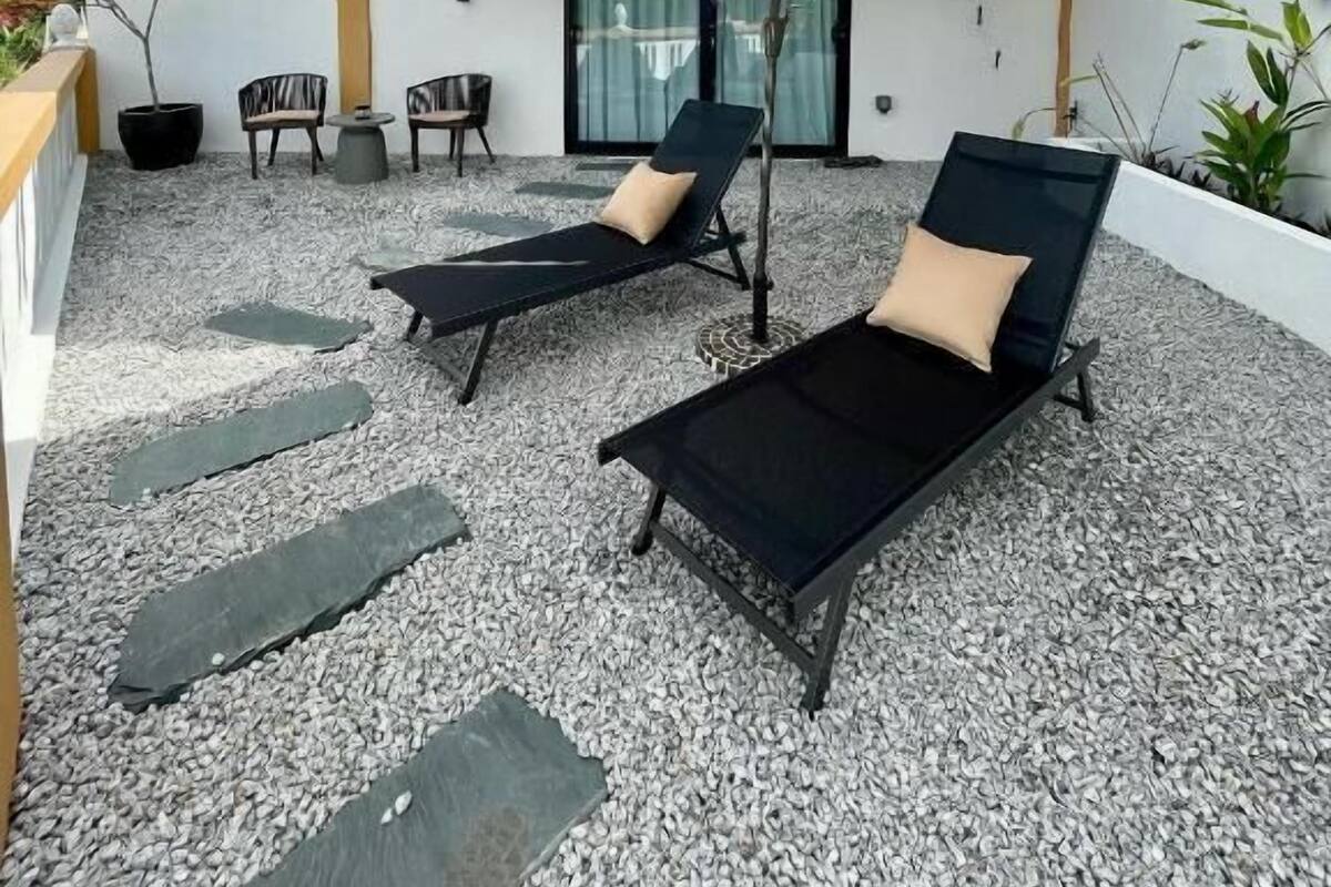 A covered outdoor seating area with two lounge chairs, a table, and an umbrella.