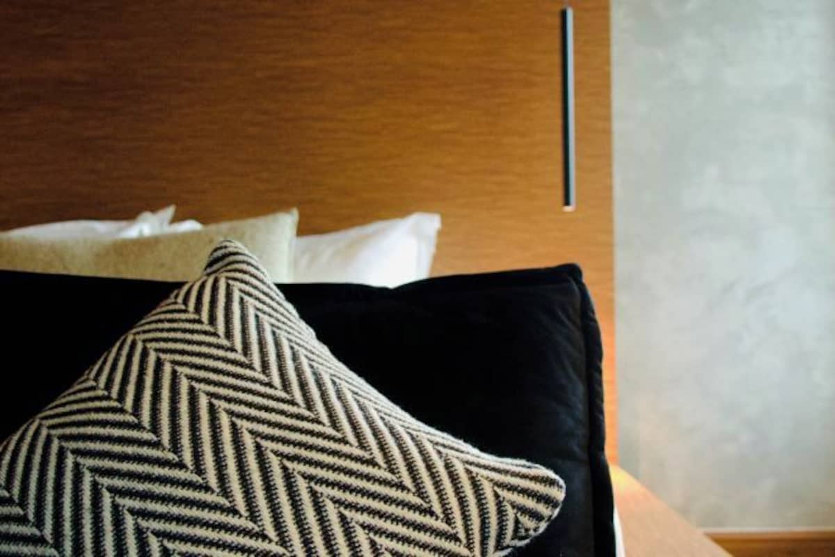 Una cama con un cojín negro y uno estampado.