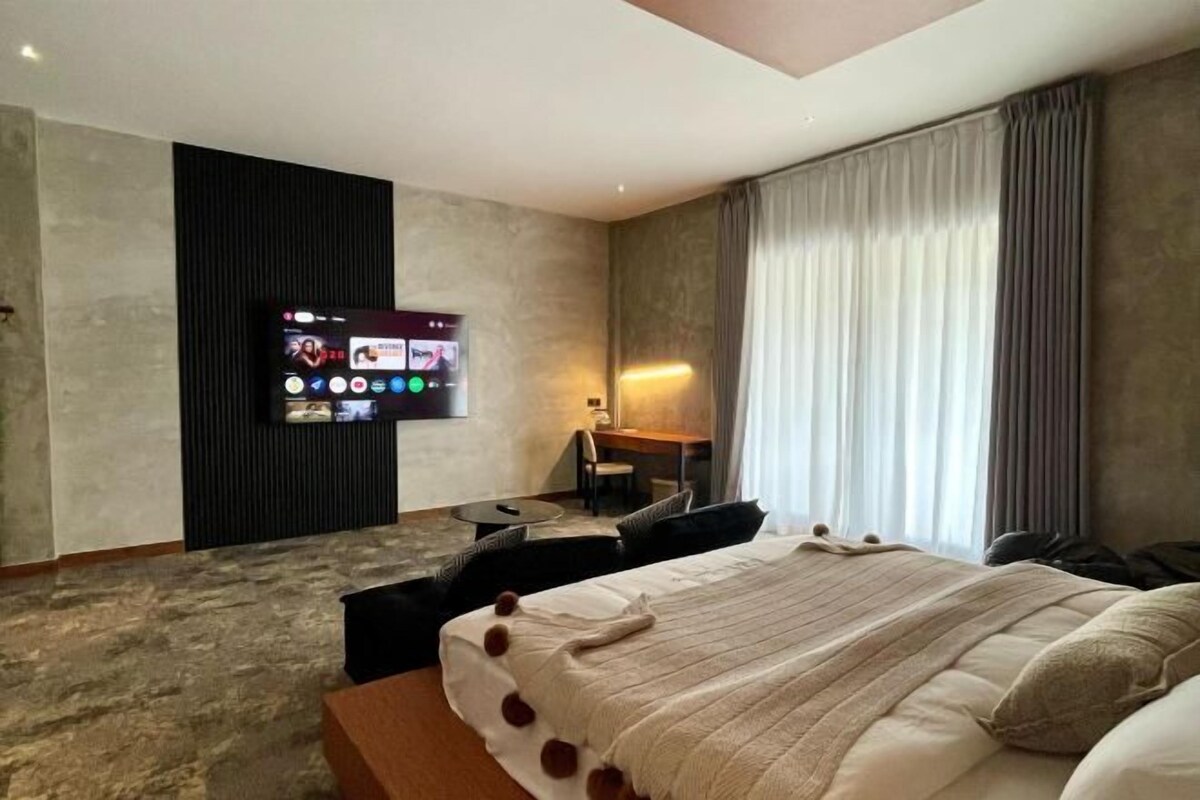 Una habitación de hotel moderna con una cama grande, un escritorio y un televisor montado en la pared.