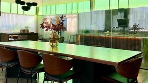A modern dining area with a long table, six chairs, and a vase with flowers. - BaBa Boutique House Langkawi (Langkawi)