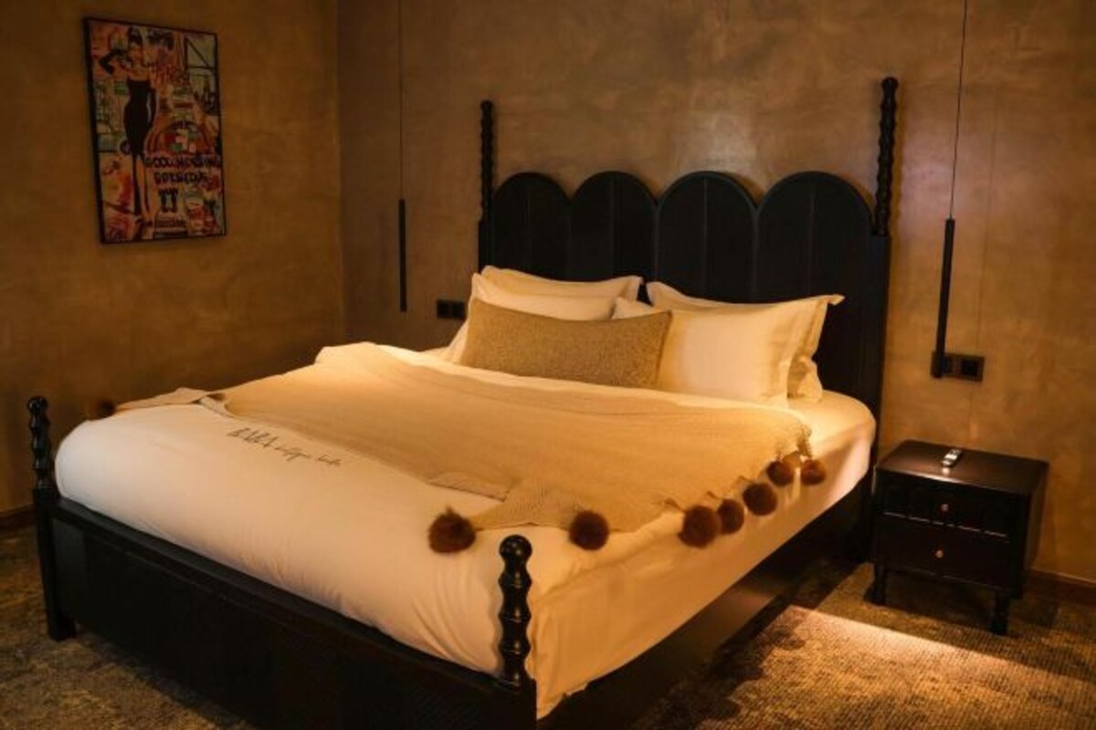 Una cama bien hecha con un cabecero oscuro y una mesita de noche pequeña.