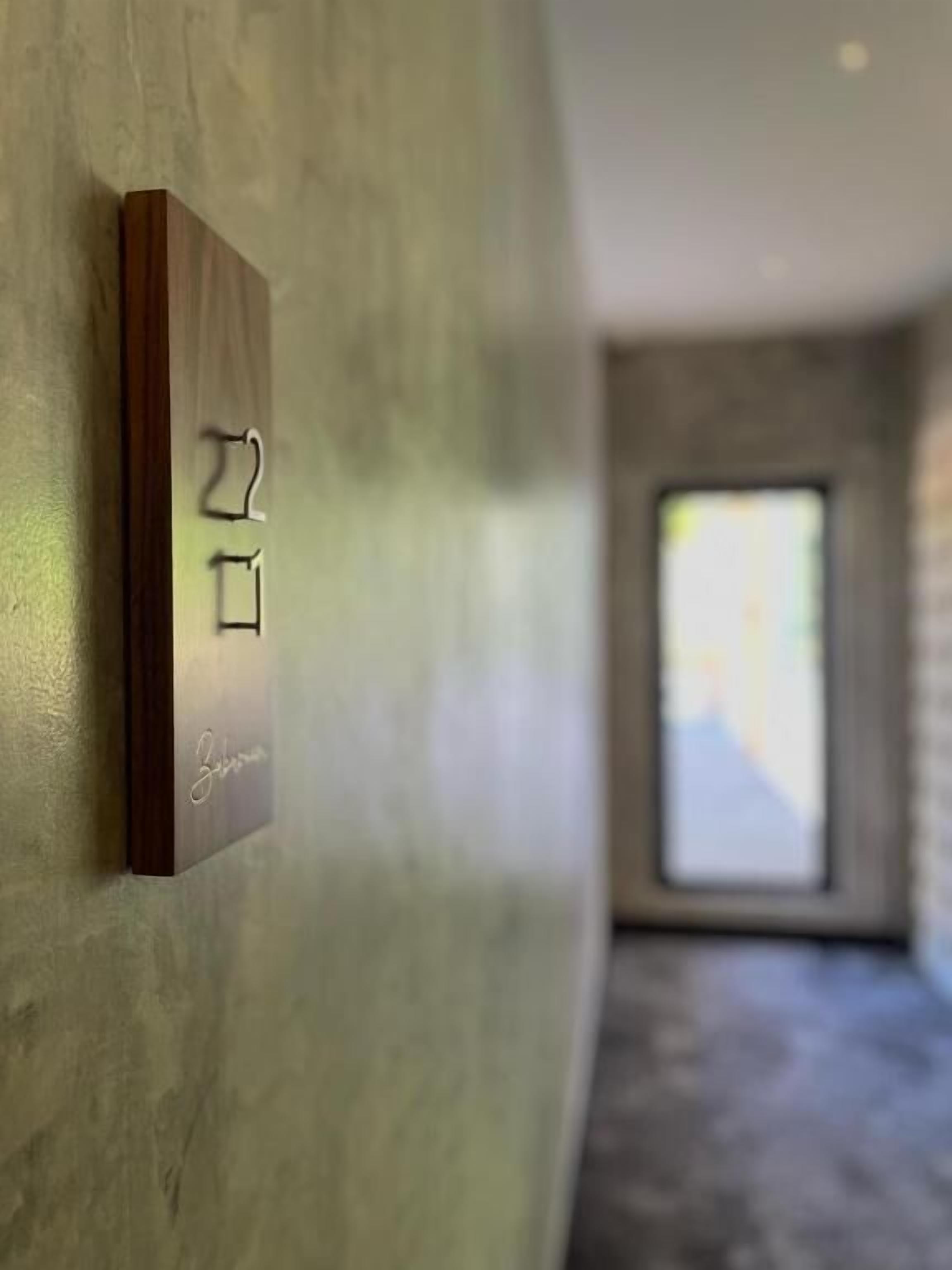 A wall-mounted light switch with a wooden panel and a nameplate.