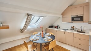 Eine moderne Küche mit Einbauofen, Mikrowelle und einem Essbereich mit rundem Tisch und Stühlen.