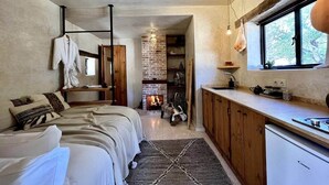A cozy bedroom with a bed, bedside table, and a fireplace.