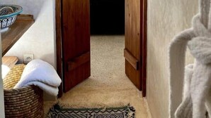 A narrow hallway with wooden doors leading to a bedroom.