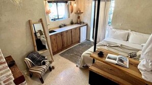 A compact bedroom with a bed, bedside table, and a small seating area. - The Gate House Studio Sidi Kaouki (Douar Iskoha)