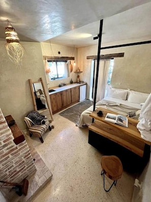 A compact bedroom with a bed, bedside table, and a small seating area.
